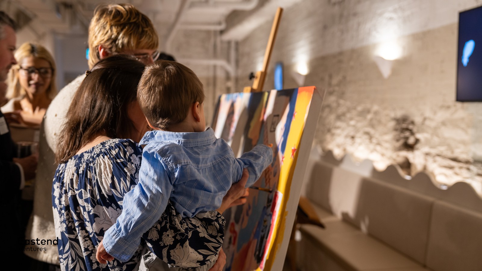 A guest holds a child painting at the easel during the Eastend Ventures Fund 1 launch event